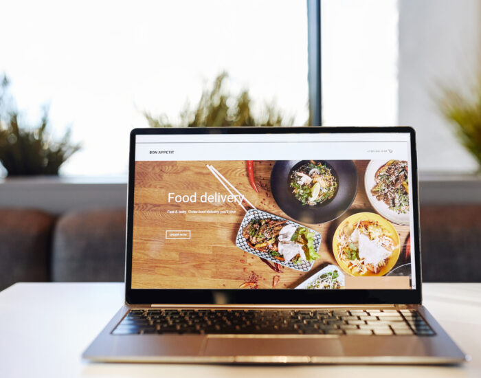 Background image of opened laptop with Food delivery website on table in cafe, copy space