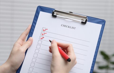 Woman filling Checklist on blurred background, closeup