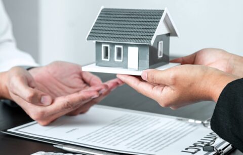 Sale Estate agent giving house model to new client after signing agreement contract with approved property form, Home Insurance and Real estate investment concept.